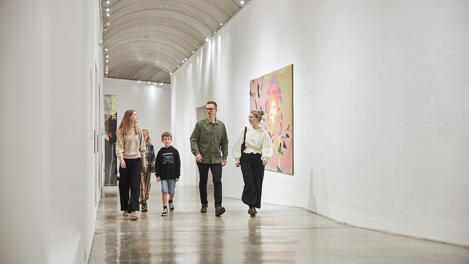Eine Familie geht den langen Korridor entlang, der mit faszinierenden Kunstwerken gefüllt ist. Sie haben einige der vielen Angebote des Museums für Familien mit Kindern kennengelernt.