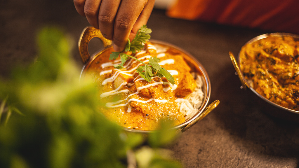 En kok er ved at pynte signaturretter fra køkken i Paladspassagen Social Dining med bredbladet persille