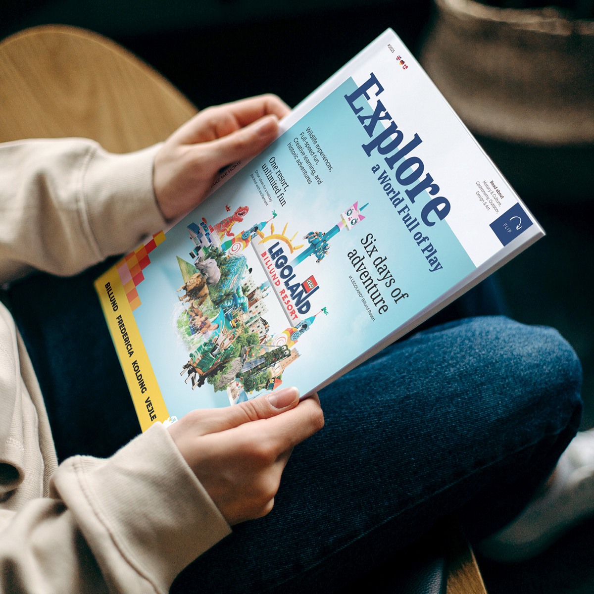 En person holder Explore magasinet med LEGOLAND Billund Resort Key visual på forsiden