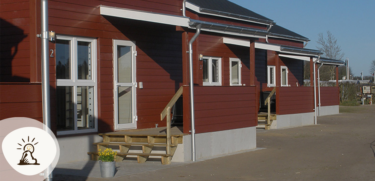 Røde træhytter med små terrasser på Vorbasse Camping, et af overnatningsstederne på Kunstruten i Small Wonders – Heart of Jutland.